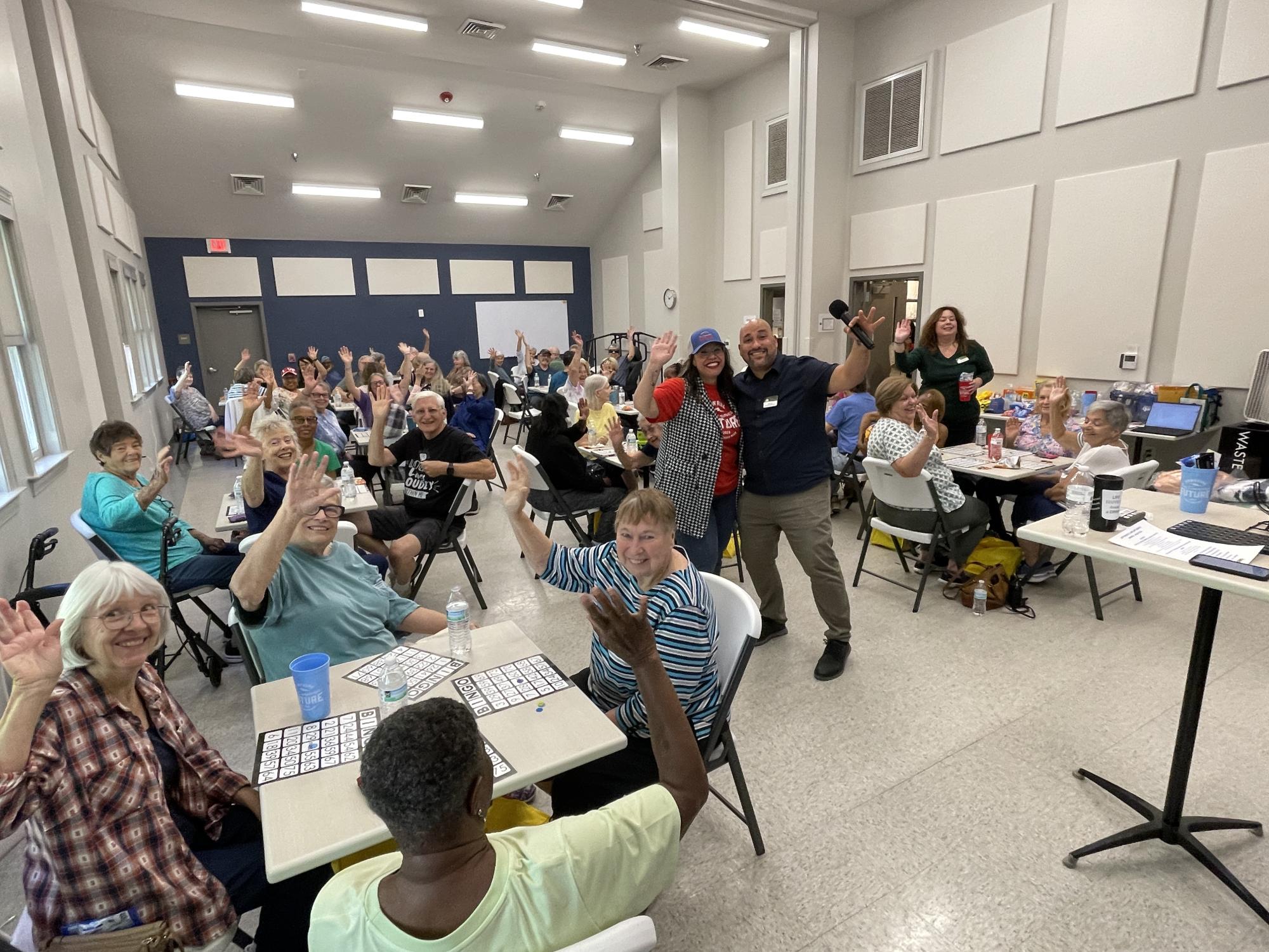 Crowd at Savings for Seniors Bingo waving to the camera