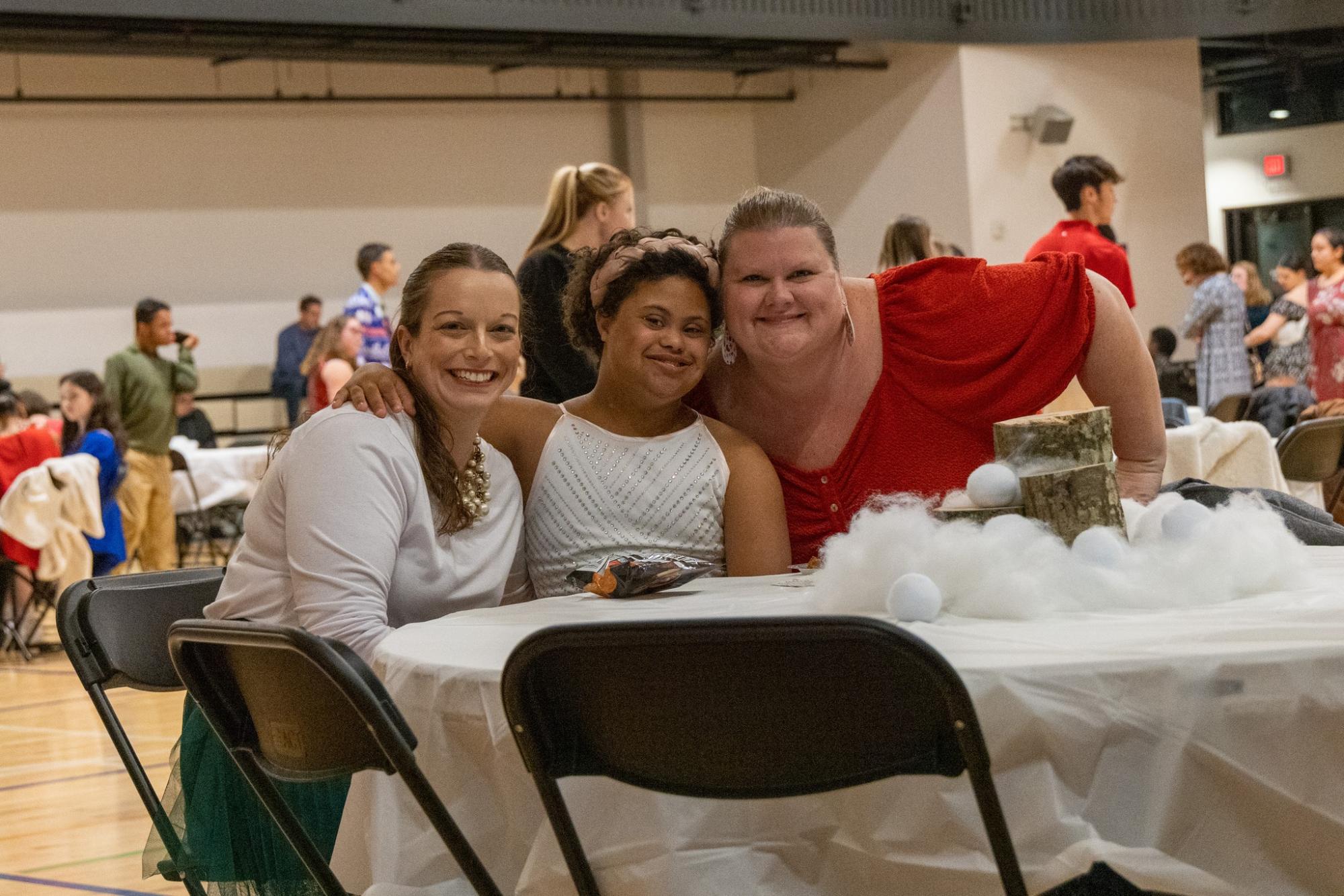 Three people sitting at a decorated table during a social event.